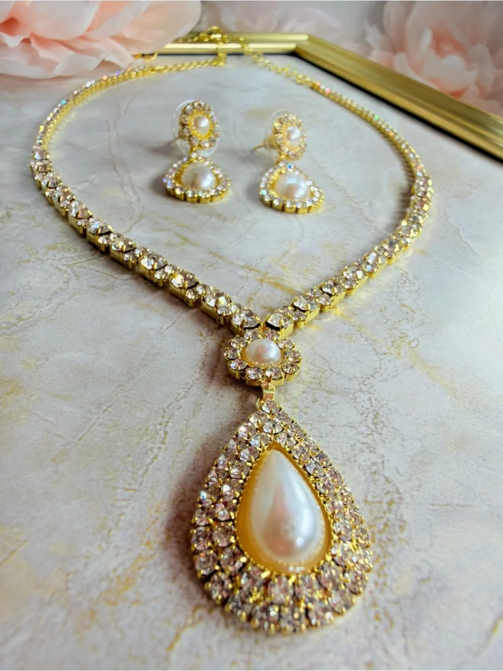 Elegant gold-tone necklace with earrings featuring a white teardrop pearl pendan